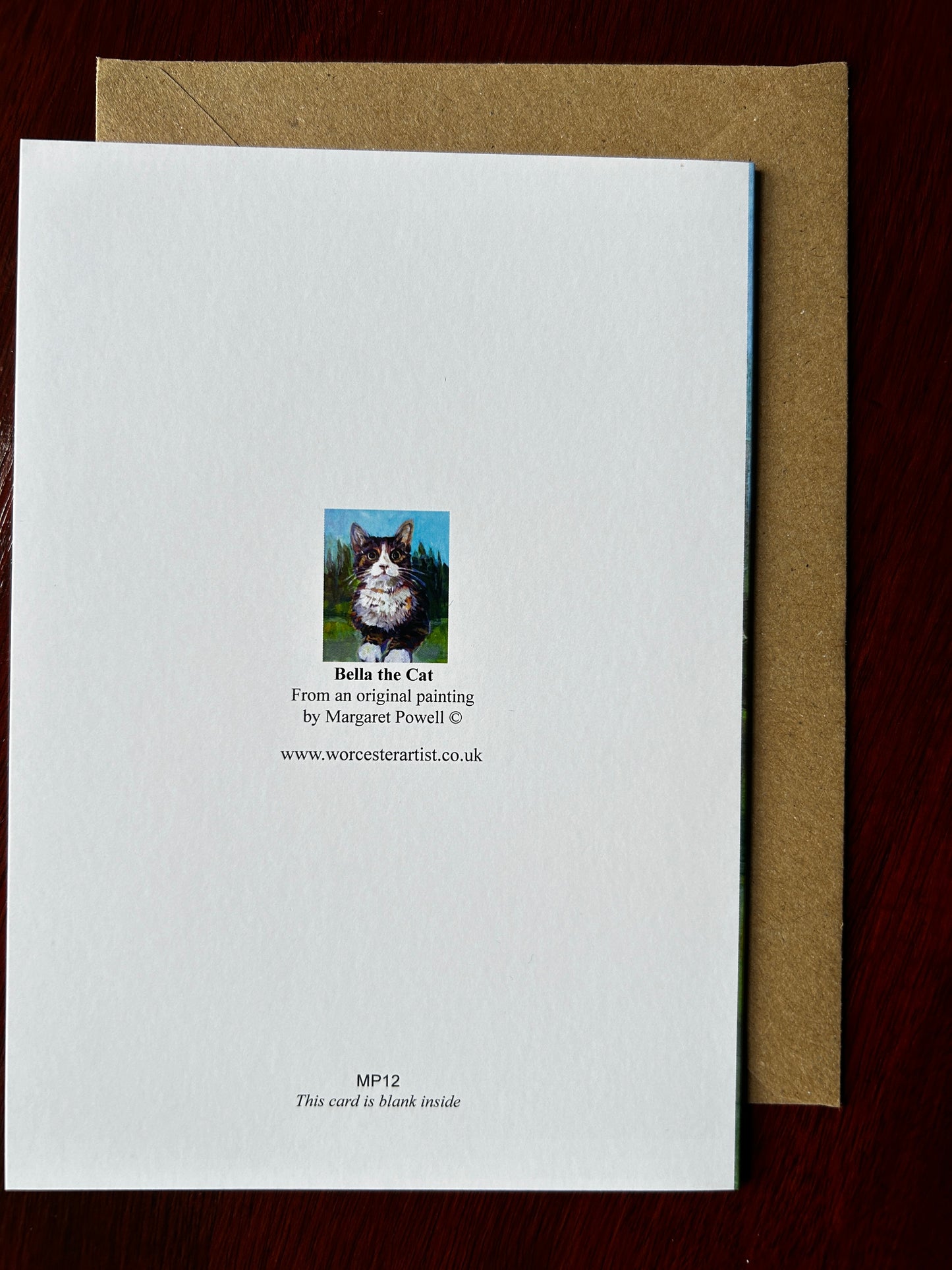 Reverse of Greetings card of Bella the Kitten painted with trees and grass in background.