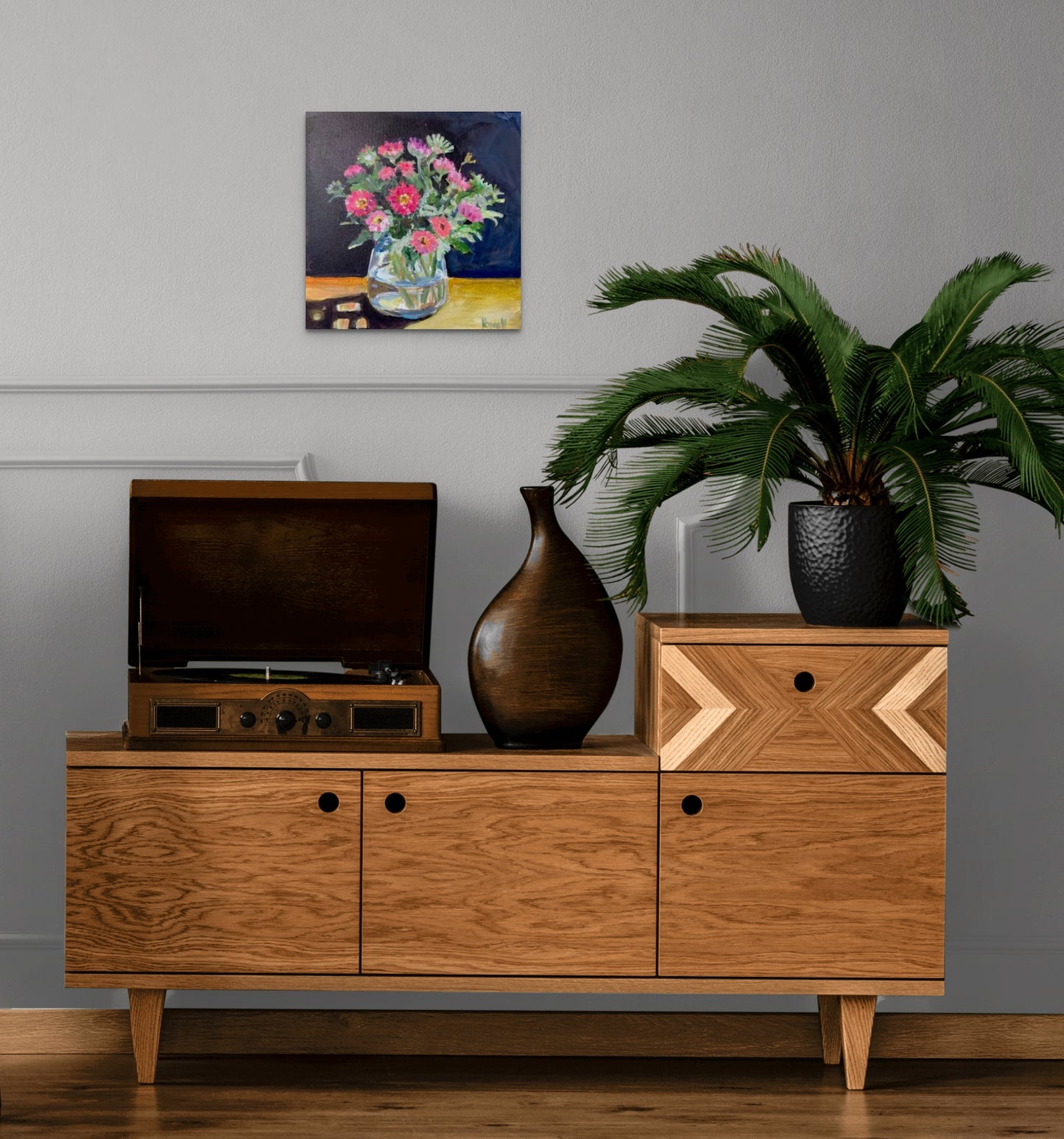 Fine art painting of Asters in the Afternoon Sun by Worcester artist Margaret Powell. Displayed on a white wall with wooden cabinet in front and large exotic plant on cabinet.